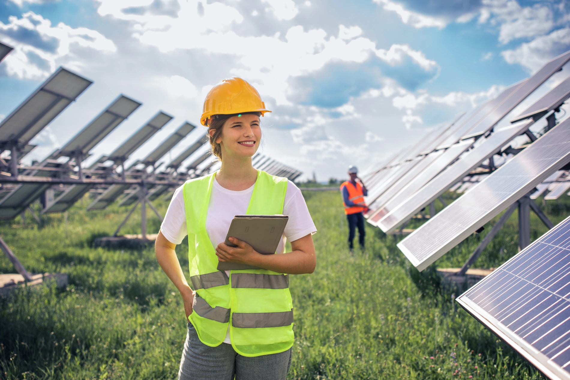 Frau mit Helm in einem Solarfeld auf einer Wiese